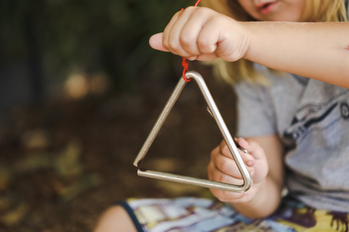 Child playing musical instruments outdoors at kindergarten